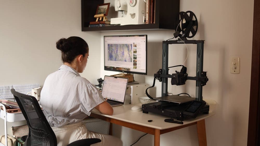 A workbench with a desktop 3D printer and filament, lit by daylight