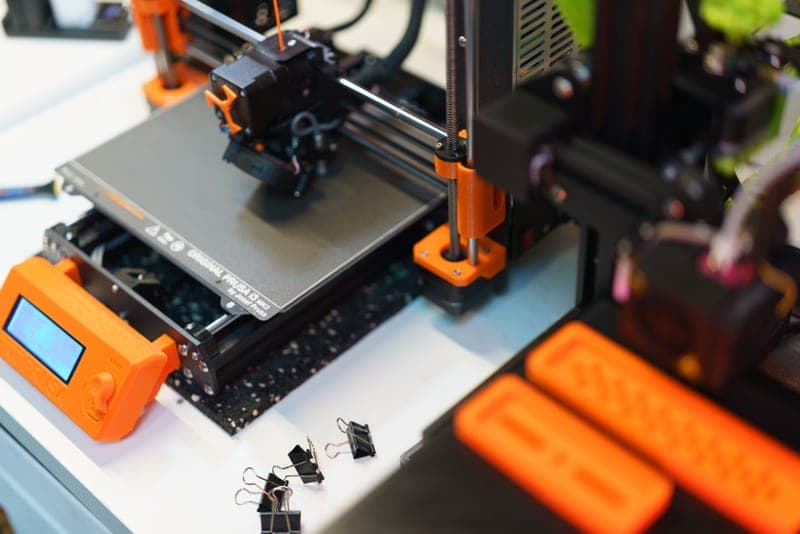 An open-frame bed-slinger 3D printer with a filament spool alongside it