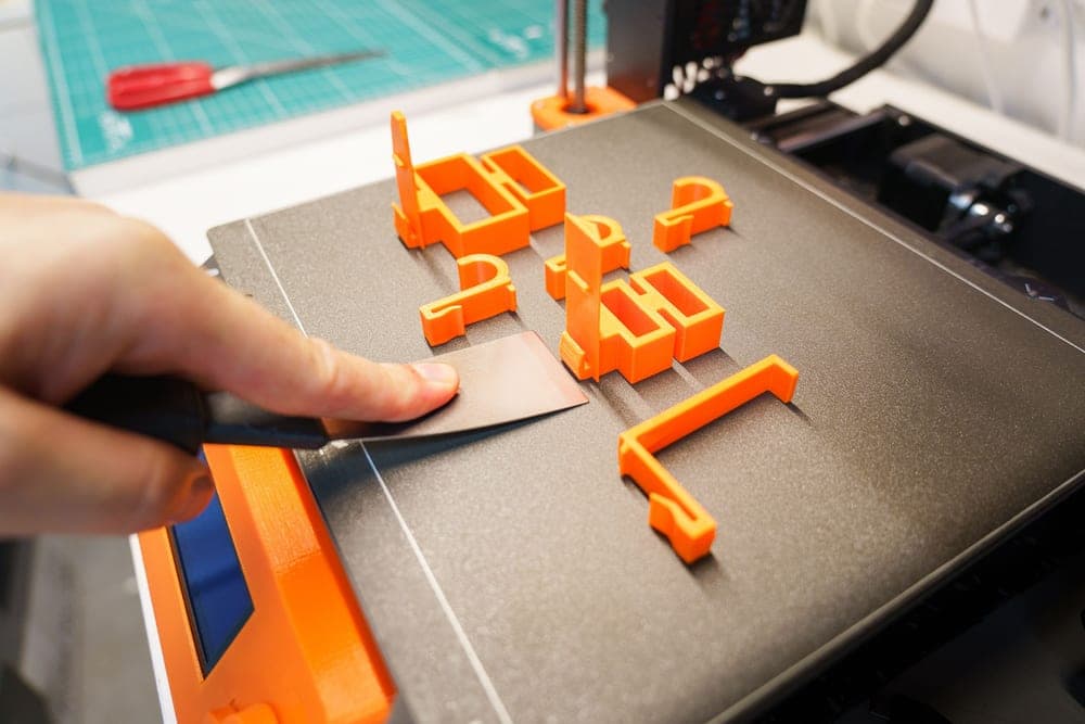 A warped printed part lifted at one corner on a build plate